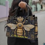 Side view of crowned queen bee handbag showing structured silhouette and black carrying handles.