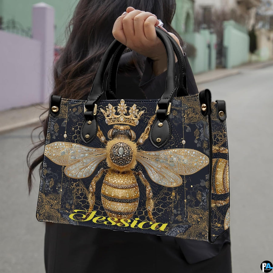 Side view of crowned queen bee handbag showing structured silhouette and black carrying handles.
