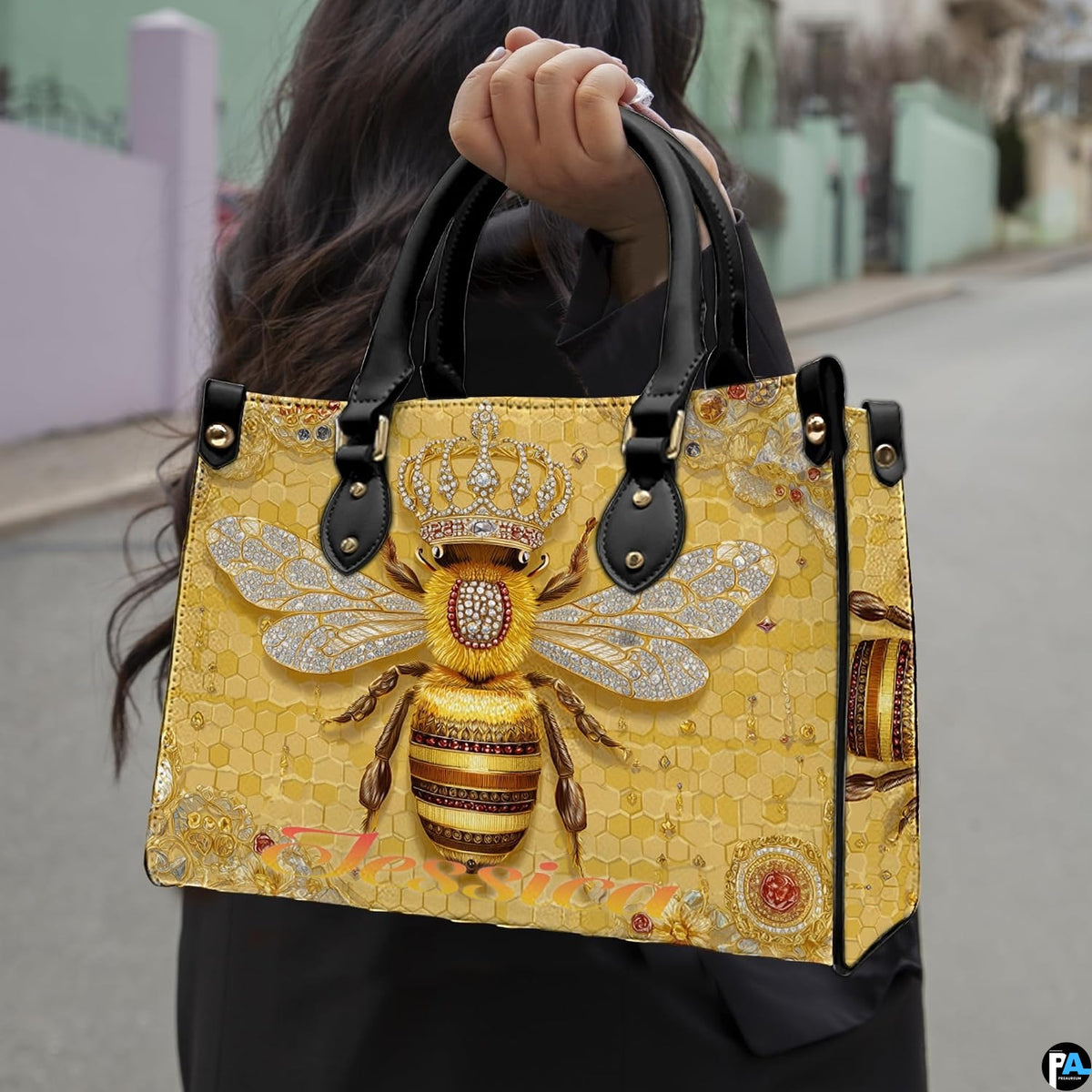 Front view of bee handbag featuring crowned queen bee illustration and geometric honeycomb background.