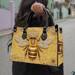 Front view of bee handbag featuring crowned queen bee illustration and geometric honeycomb background.