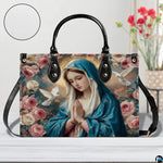 Lifestyle tabletop view of Virgin Mary floral handbag resting beside flowers.