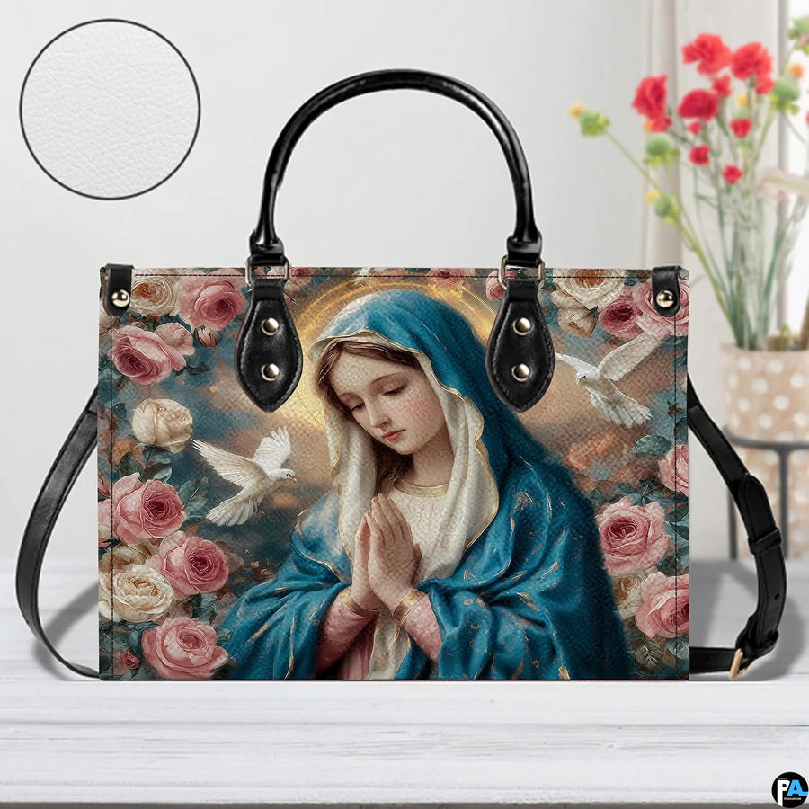 Lifestyle tabletop view of Virgin Mary floral handbag resting beside flowers.
