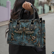 Front view of baroque teal handbag with sculpted bronze dragonfly and ornate rococo corner scrollwork
