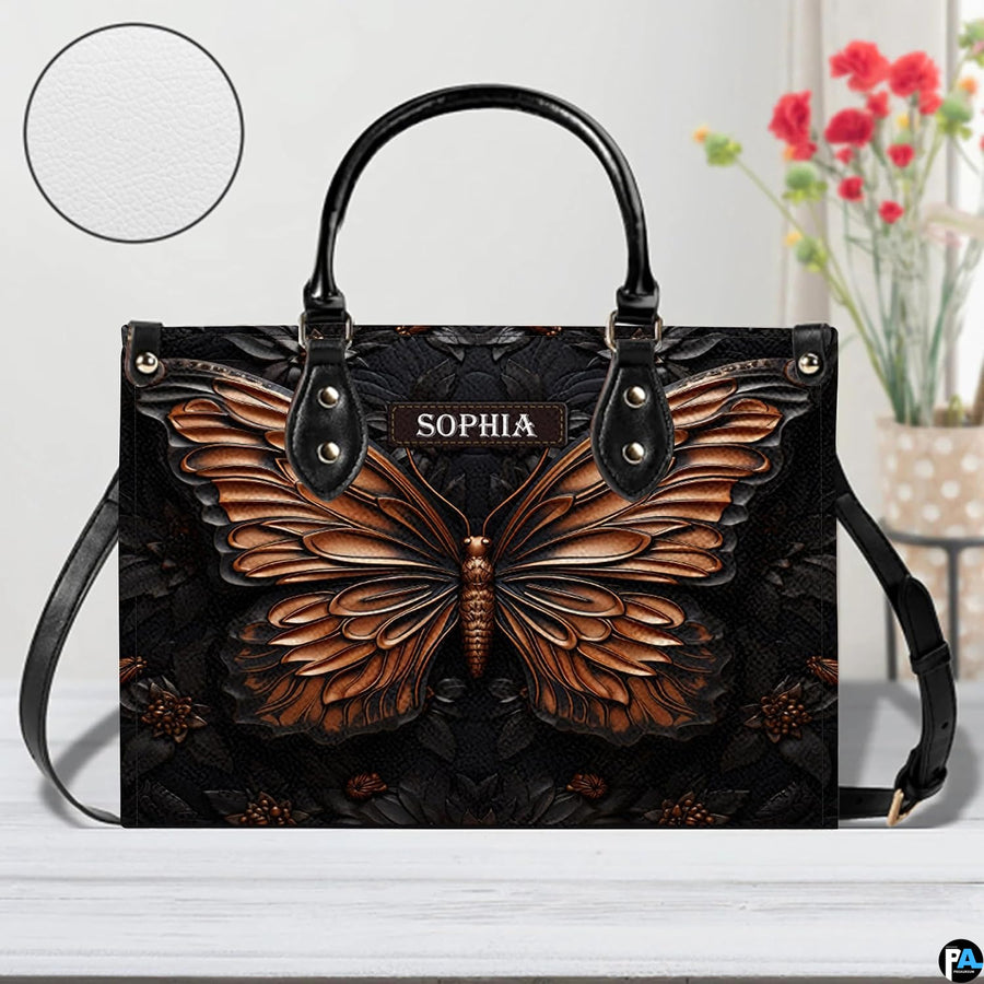Sculpted butterfly handbag shown on a white tabletop beside floral accents and a circular material swatch.