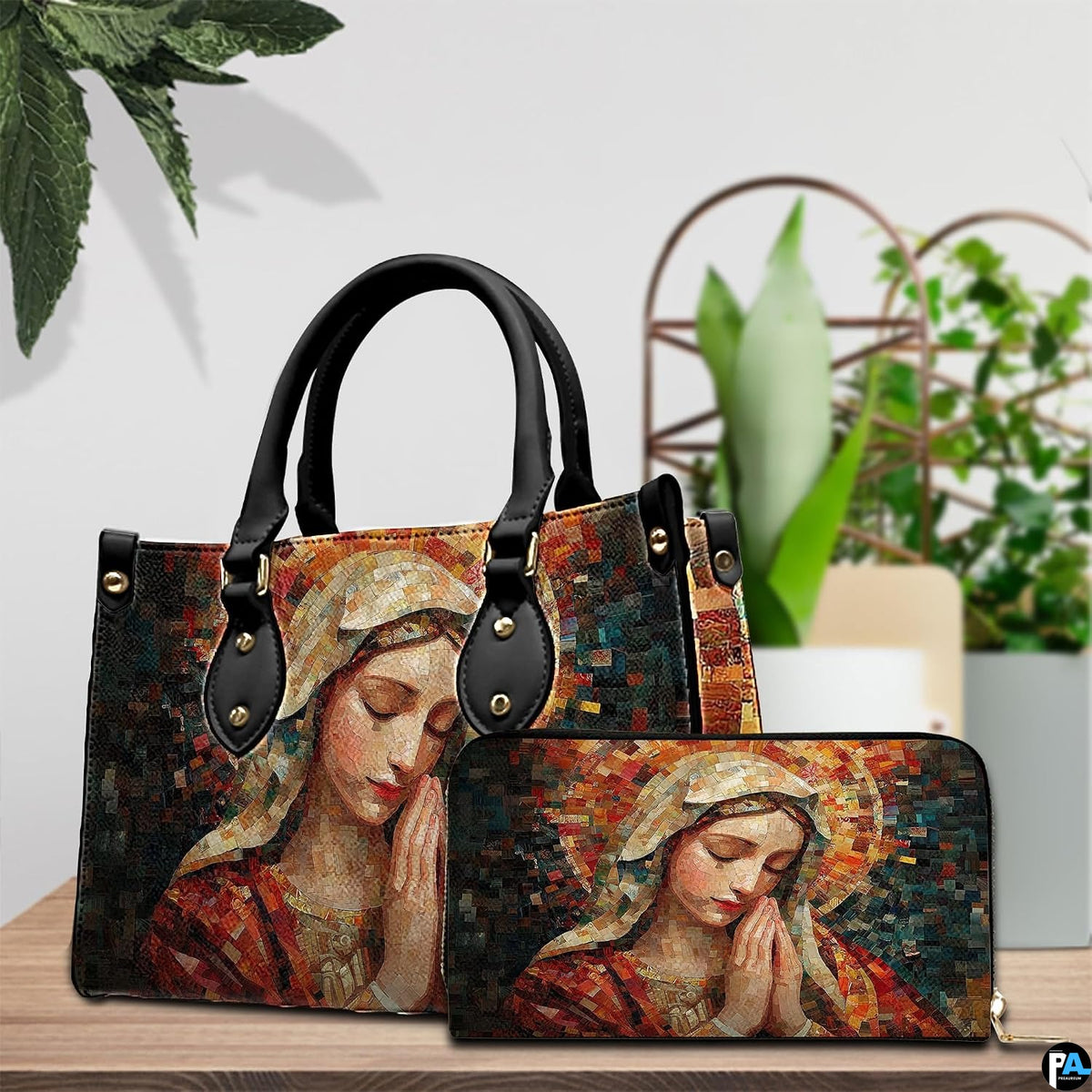 Handbag and matching wallet with mosaic Praying Mary artwork displayed beside tabletop plant.