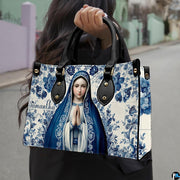 Street style lifestyle photo of model wearing blue ceramic tile Virgin Mary handbag.