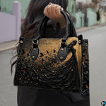 Gothic witch handbag and wallet displayed on wooden table beside potted plant.