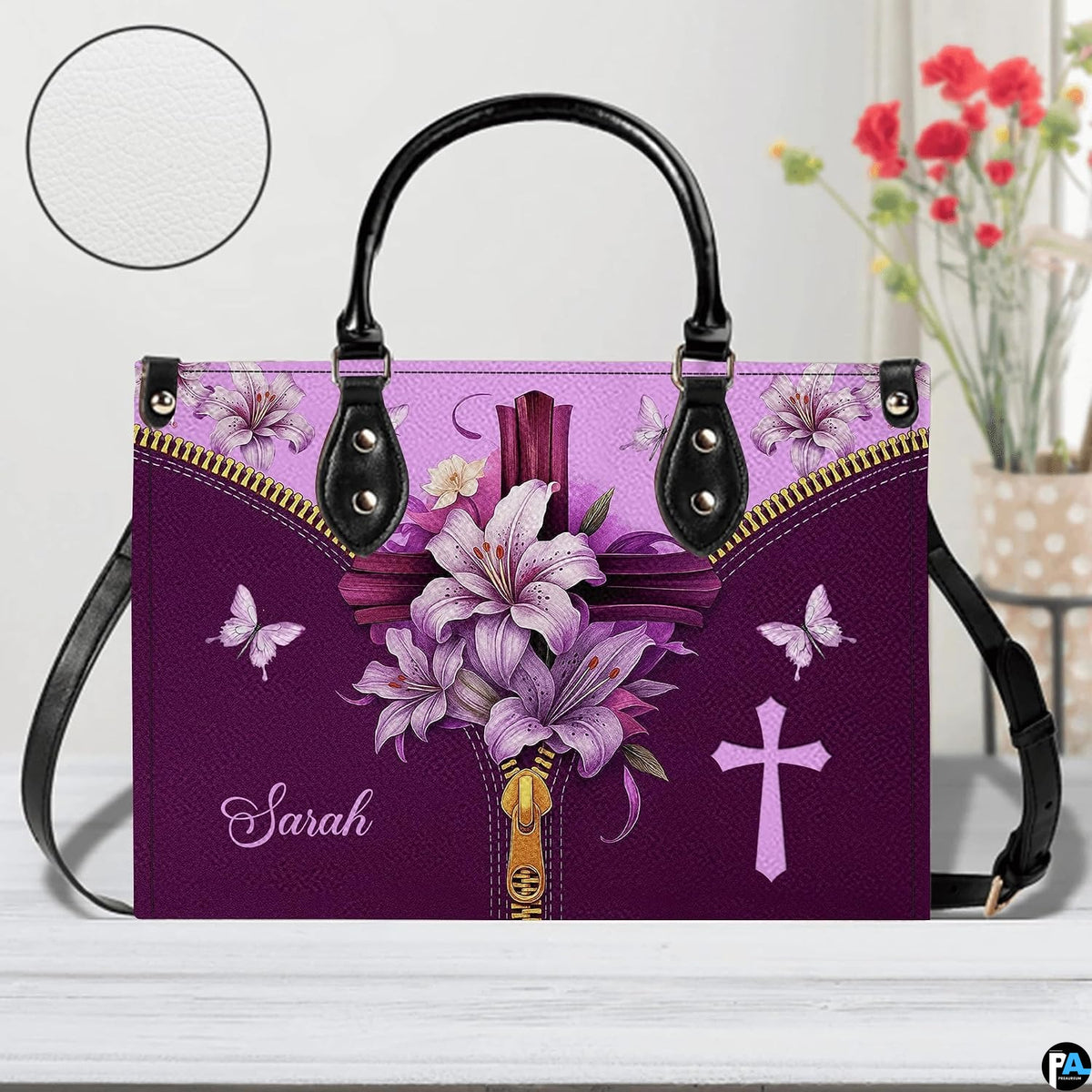 Christian cross Easter lily violet handbag displayed on white table beside floral bouquet.