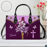 Christian cross Easter lily violet handbag displayed on white table beside floral bouquet.