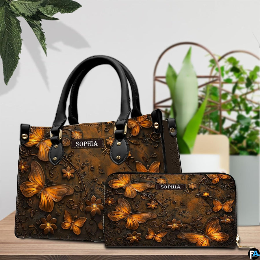 Golden butterfly handbag and matching wallet resting together on a wooden tabletop near potted greenery.