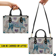 Front view of unicorn handbag displaying turquoise and lavender filigree unicorn artwork.