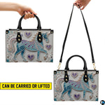 Front view of unicorn handbag displaying turquoise and lavender filigree unicorn artwork.