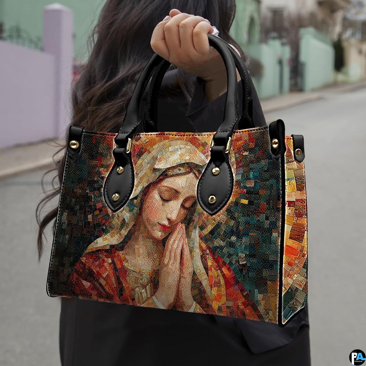 Model carrying terracotta mosaic Praying Virgin Mary handbag outdoors on street.