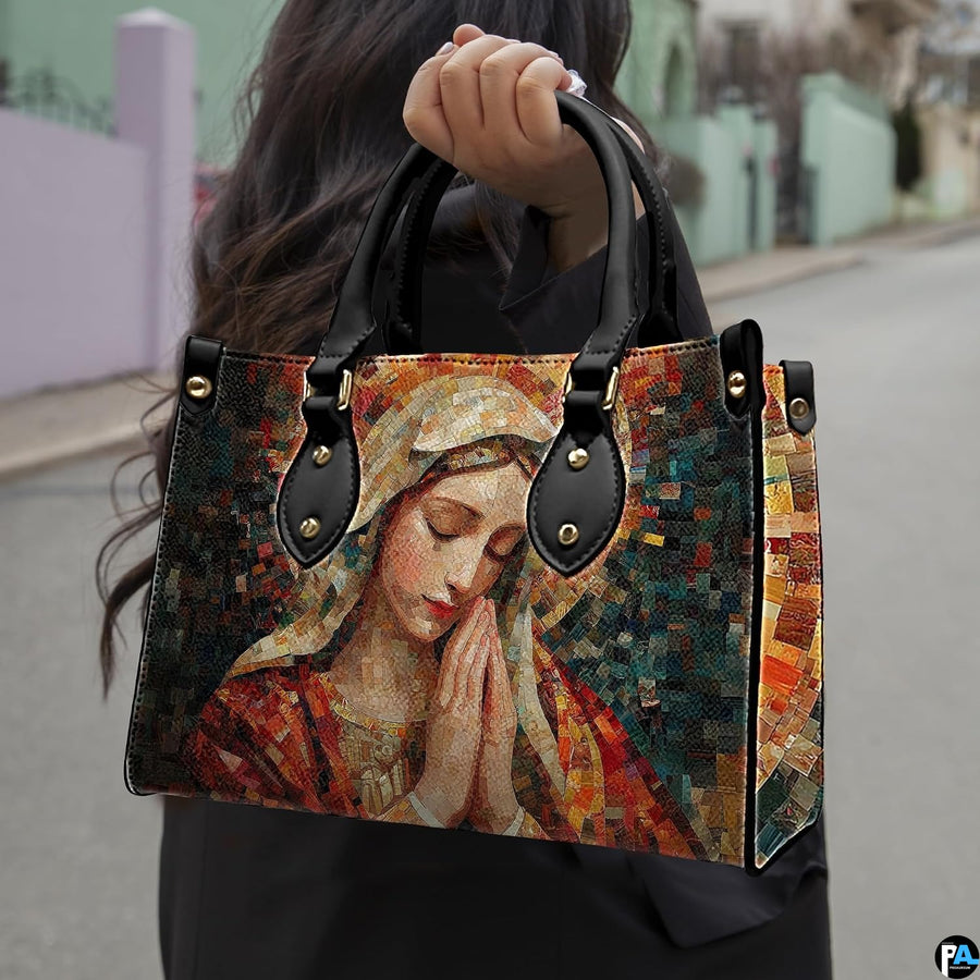 Model carrying terracotta mosaic Praying Virgin Mary handbag outdoors on street.
