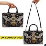 Side profile of queen bee handbag showing structured silhouette and black carrying handles.