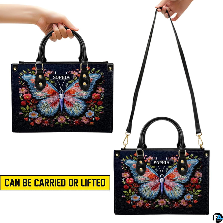 Carrying options demonstrated for the navy floral butterfly handbag with handheld and shoulder wear.