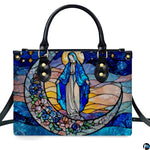 Stained glass art of the Virgin Mary on a floral crescent moon against a starry sky printed on a structured handbag.
