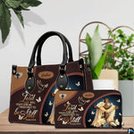 Christian wooden cross handbag and matching wallet set on wooden table near houseplant.