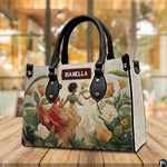 Angled cafe view of the structured floral artwork handbag resting on a polished wooden surface.