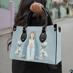 Lifestyle model carrying the minimalist Virgin Mary devotional handbag on city street