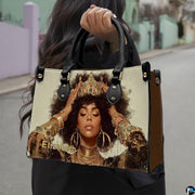 Woman carrying royal afro portrait handbag with gold crown and layered jewelry