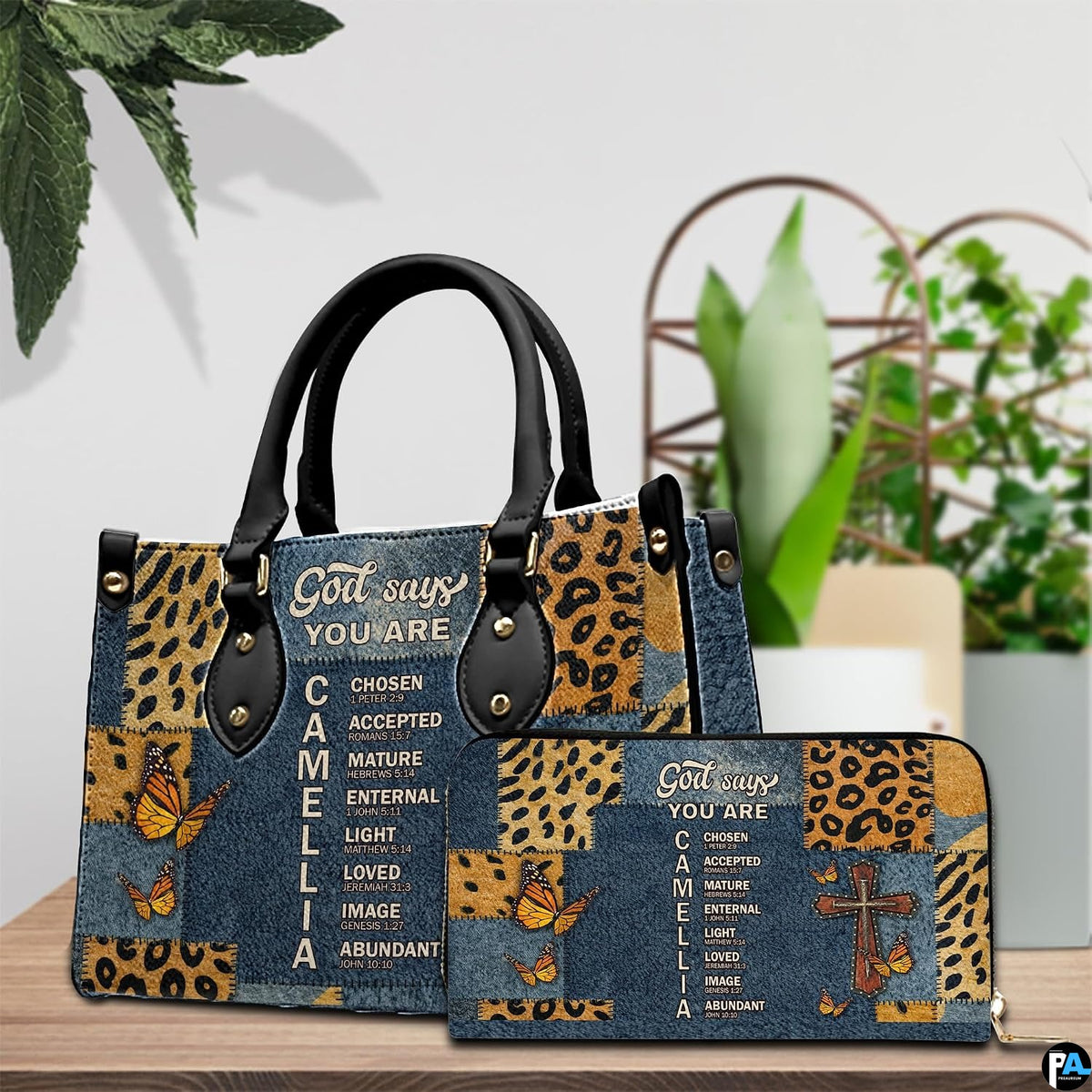 Tabletop display showing Christian cross butterfly handbag and matching wallet beside indoor plants