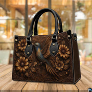 Close view of dimensional floral relief and ornate corner scrollwork on botanical handbag.
