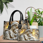 Tabletop display showing carved Madonna handbag and matching wallet beside potted house plants.