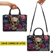 Filigree skull handbag carrying demonstration showing top handle and shoulder strap carry.