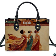 Direct studio front view of the structured handbag featuring three royal African women in ornate dresses.