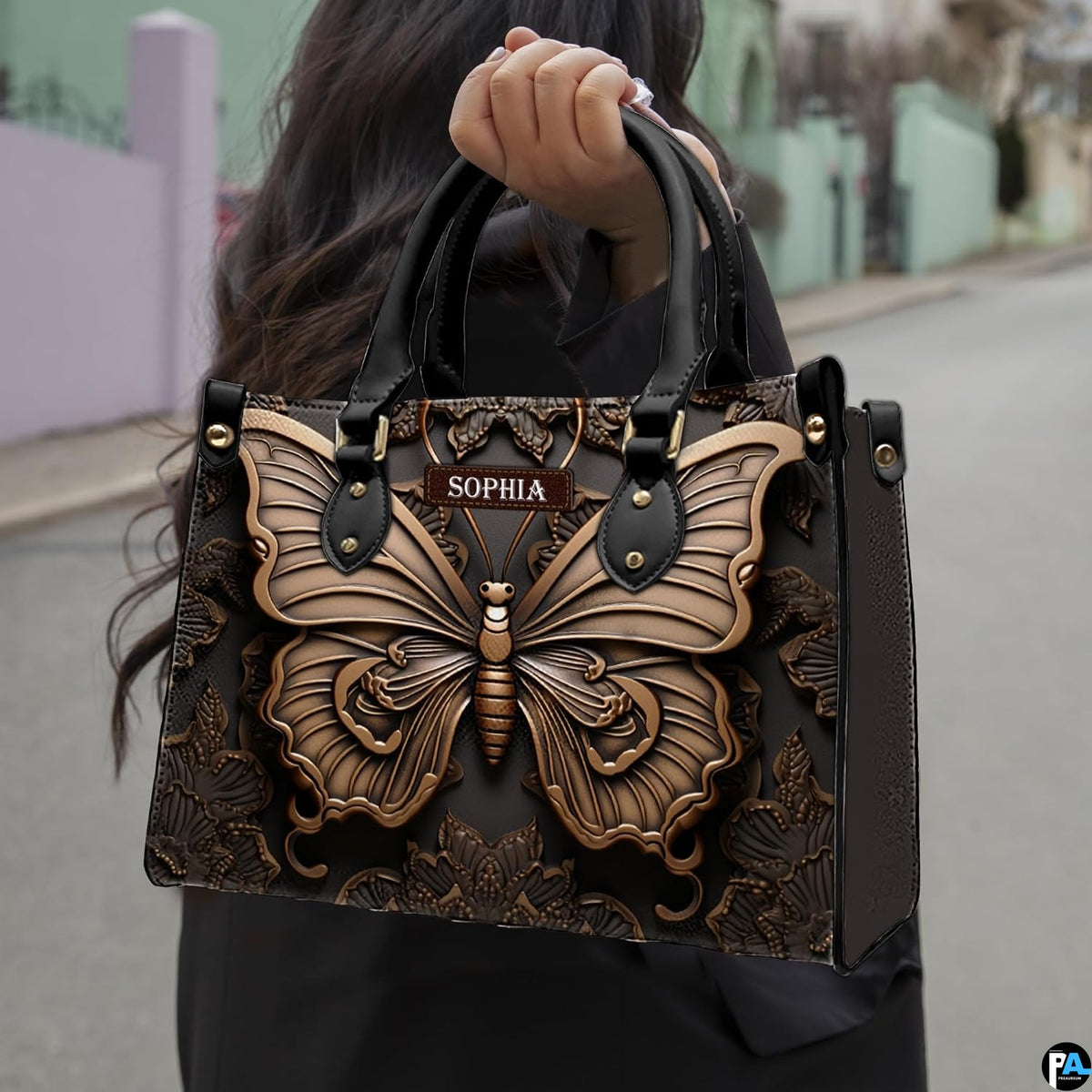 Outdoor street view of a model carrying the sculpted bronze butterfly handbag by its top handles.