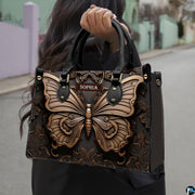 Outdoor street view of a model carrying the sculpted bronze butterfly handbag by its top handles.