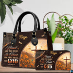 Detailed view of arched sunrise scene featuring wooden cross on flowering hillside on handbag.