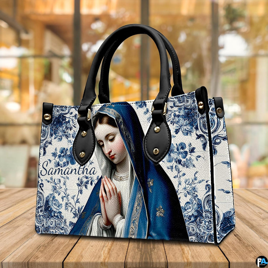 Cobalt tile praying Virgin Mary handbag arranged on wooden tabletop.