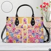 Front view of floral cross handbag on white tabletop with circular textured exterior swatch.