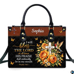 Hummingbird cross handbag and wallet displayed on wooden table beside potted plant.