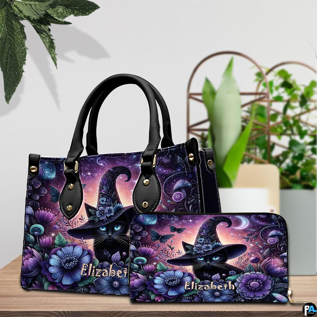 Indoor arrangement showing floral witch cat artwork and companion accessory beside potted plants.