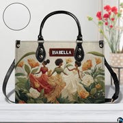 Tabletop perspective of the floral dancing women handbag displayed with decorative blooms.