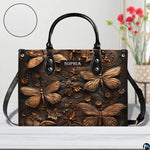 Artisan dragonfly handbag displayed on a white surface alongside floral decor and a circular material swatch.