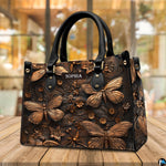 Sculpted dragonfly handbag resting on a sunny outdoor wooden deck in front of cafe windows.