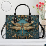 Front view of gold dragonfly handbag on white table with floral vase and texture swatch inset
