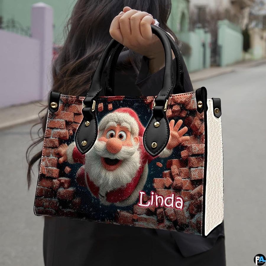 Person carrying brick wall Santa top-handle bag outdoors along a city street.