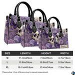 Lavender skull handbag and wallet displayed on wooden table beside potted plant.