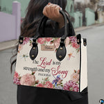 Scripture floral dragonfly handbag held by handle while walking outdoors along a street.