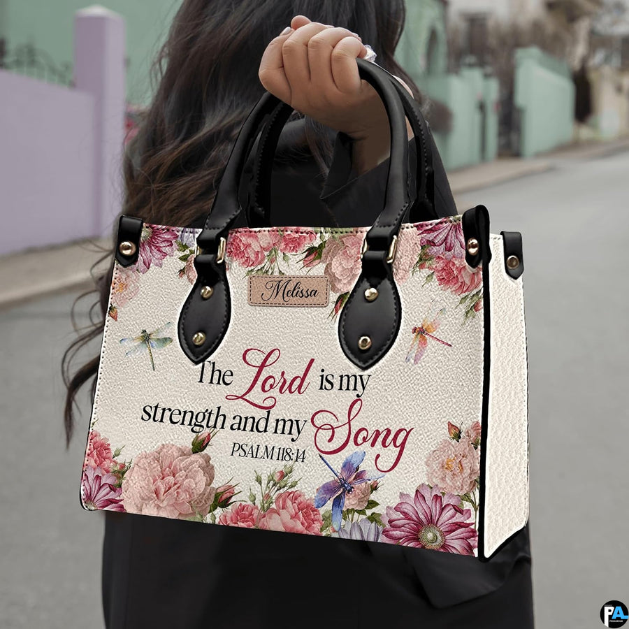 Scripture floral dragonfly handbag held by handle while walking outdoors along a street.