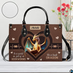 Close-up detail of handbag highlighting textured surface, heart accents, and golden dragon artwork