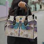 Front view of dragonfly handbag showing stained-glass wings and golden arabesque scrollwork.