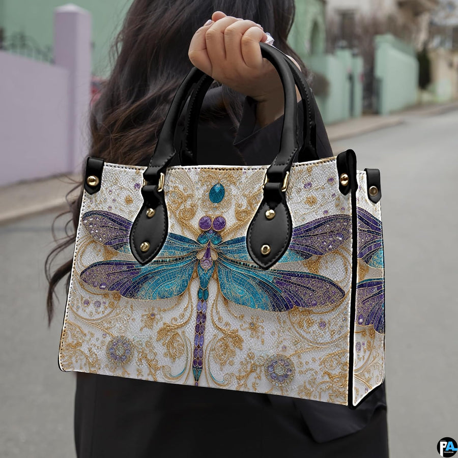 Front view of dragonfly handbag showing stained-glass wings and golden arabesque scrollwork.