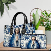 Top-handle handbag and matching wallet displayed on table next to potted plant.