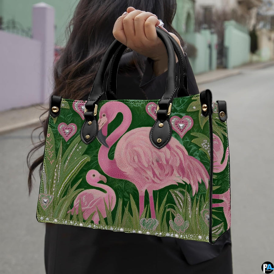 Front view of flamingo handbag displaying pink flamingos and tall green tropical foliage.